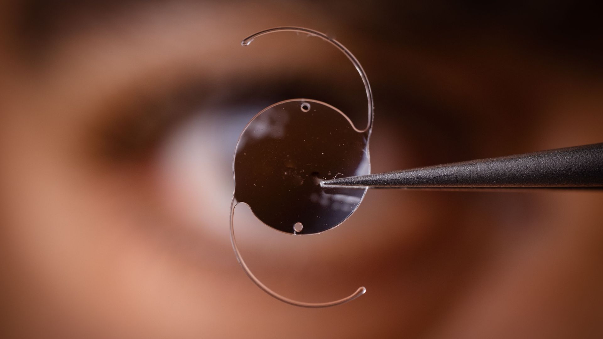 One of many implantable contact lenses are held up in front of an individuals eye.