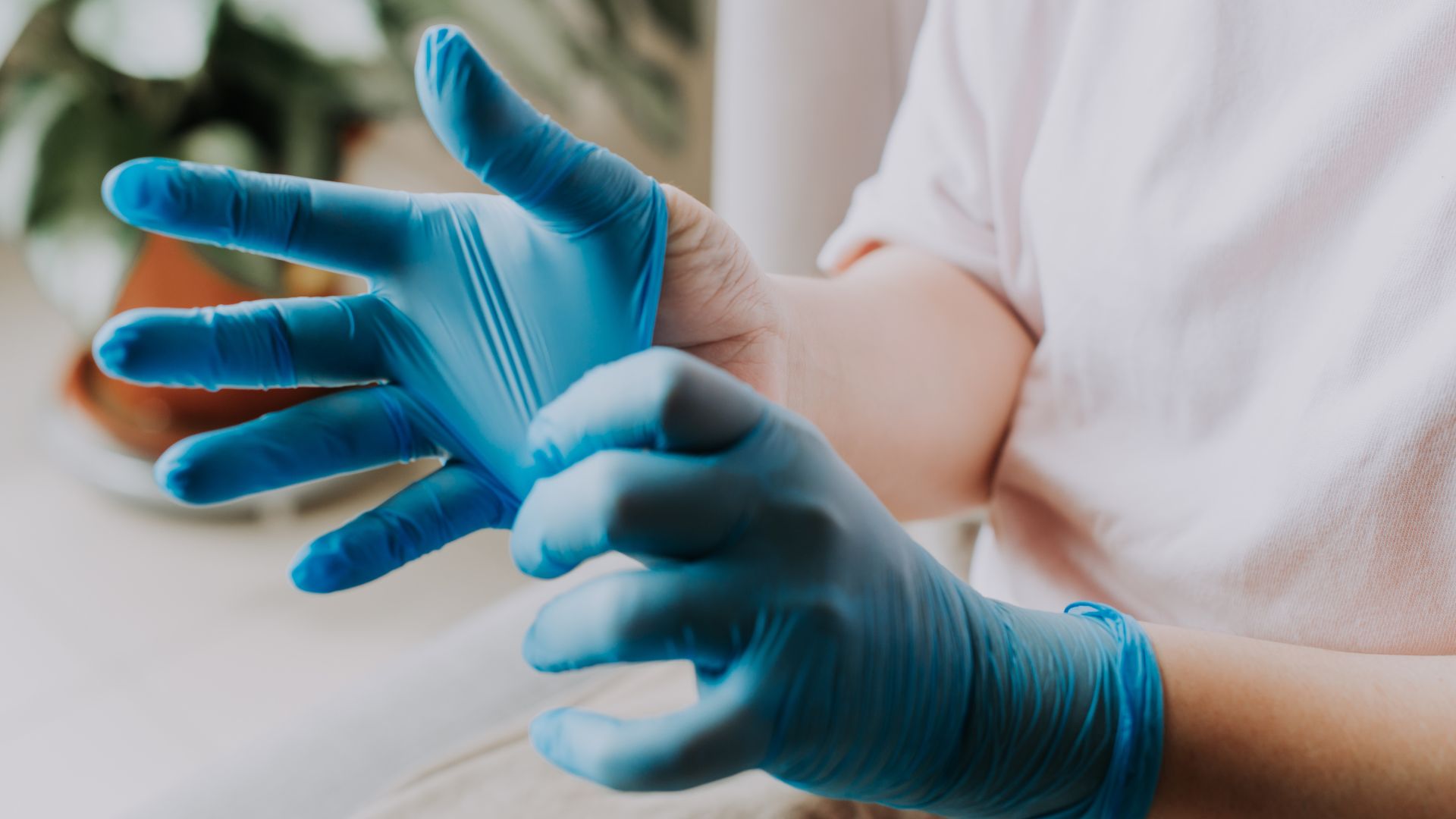 A medical professional slides on a pair of blue medical gloves.