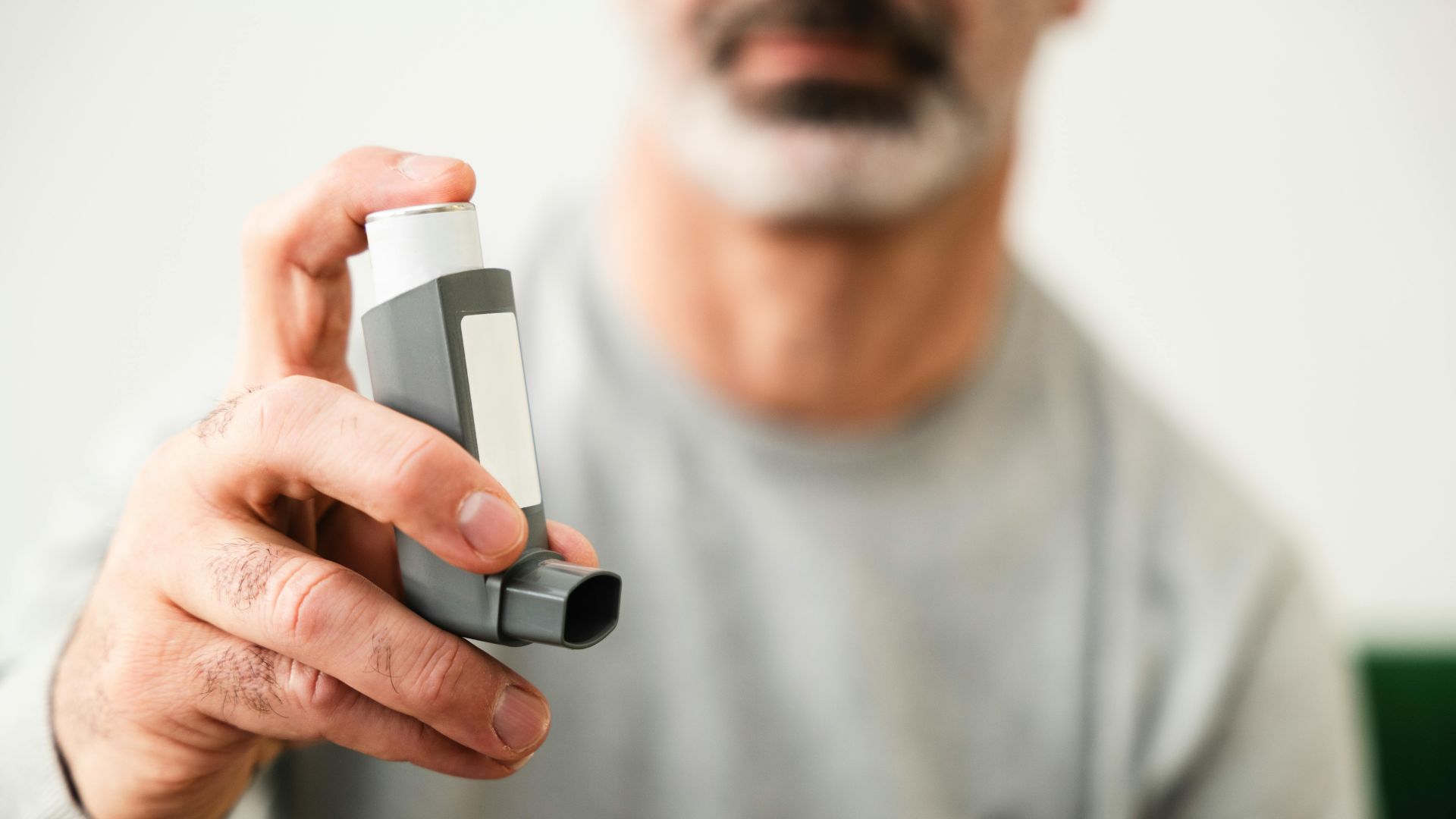 A man holds an inhaler, a medical device subject to fda registration and listing.